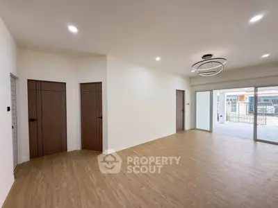 Spacious modern living room with wooden flooring and stylish lighting, featuring large sliding doors to outdoor area.