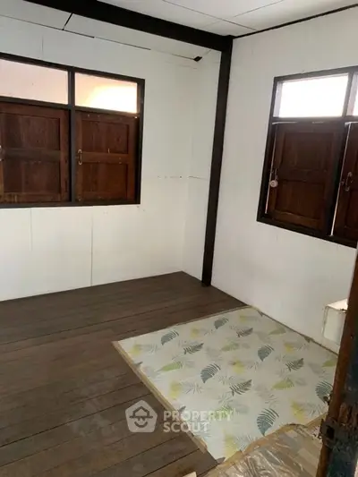 Cozy room with wooden floors and two windows, perfect for customization.