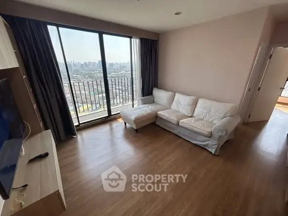 Spacious living room with large window offering stunning city view and cozy white sofa.
