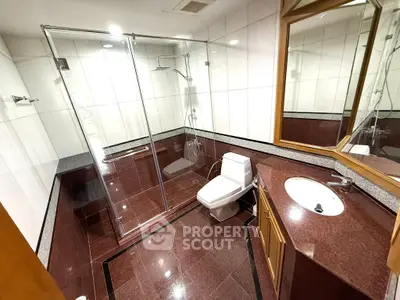 Luxurious bathroom with elegant red tile flooring and modern glass shower enclosure.