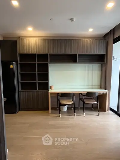Modern kitchen with sleek cabinetry and dining area in contemporary apartment.