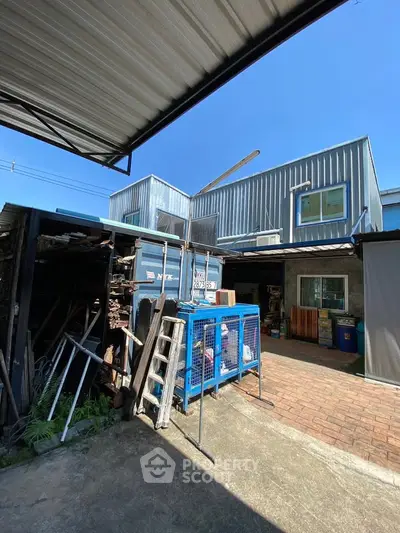 Industrial-style exterior with metal siding and open storage area under clear blue sky.