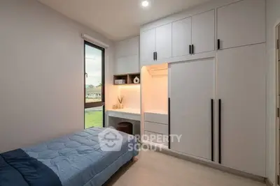 Modern bedroom with built-in storage and large window offering natural light.