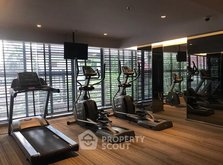 Modern gym with cardio equipment and large windows in luxury apartment complex