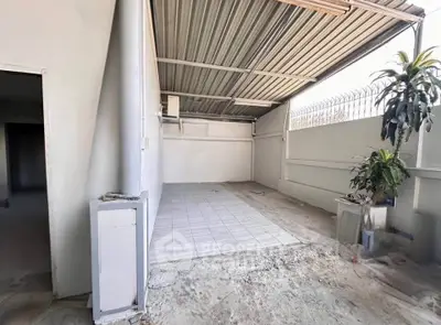 Spacious covered outdoor area with tiled flooring and potted plant, ideal for versatile use.