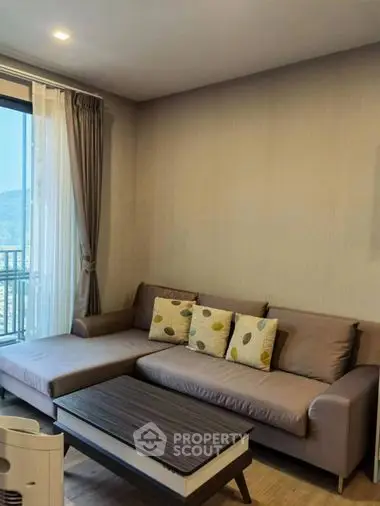 Cozy living room with modern sofa and wooden coffee table, natural light streaming through the balcony door, ideal for relaxation.