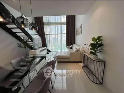 Modern living room with high ceiling and stylish decor, featuring a glass dining table and cozy seating area.