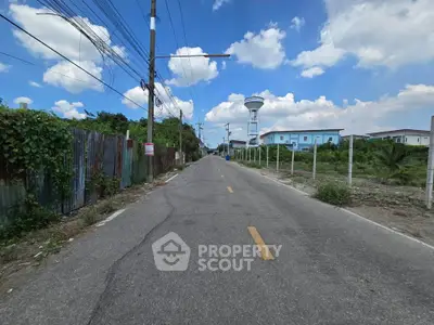 Scenic road view with clear blue sky and residential buildings in the distance, ideal for real estate development.