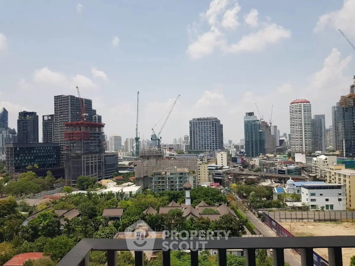 Stunning cityscape view from a high-rise balcony showcasing urban skyline and construction cranes.