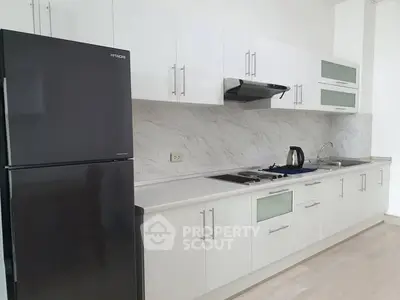 Modern kitchen with sleek white cabinets and black fridge in a stylish apartment.