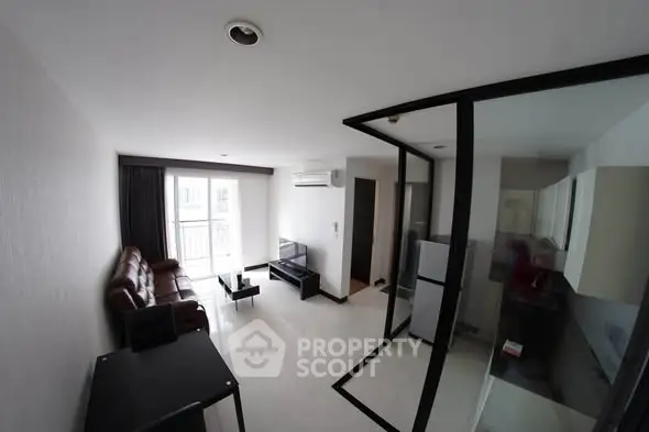 Modern living room with sleek glass partition and compact kitchen area.