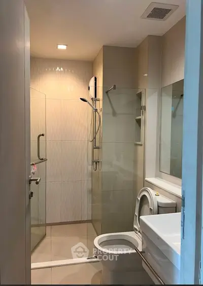 Modern bathroom with glass shower and sleek fixtures in a contemporary apartment.