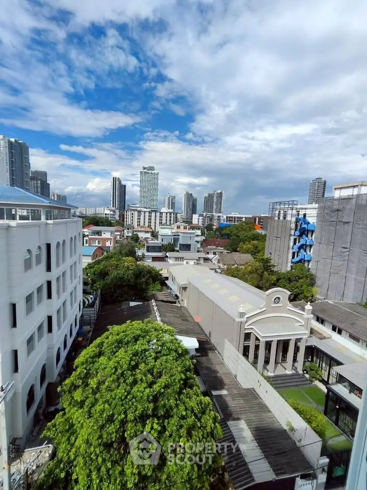 Stunning cityscape view from a high-rise building showcasing urban skyline and lush greenery.