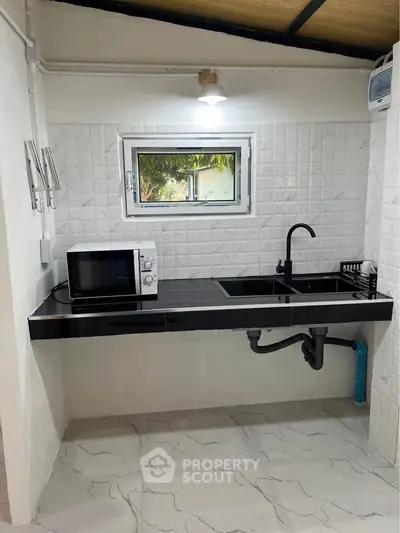 Modern minimalist kitchen with black countertop and microwave