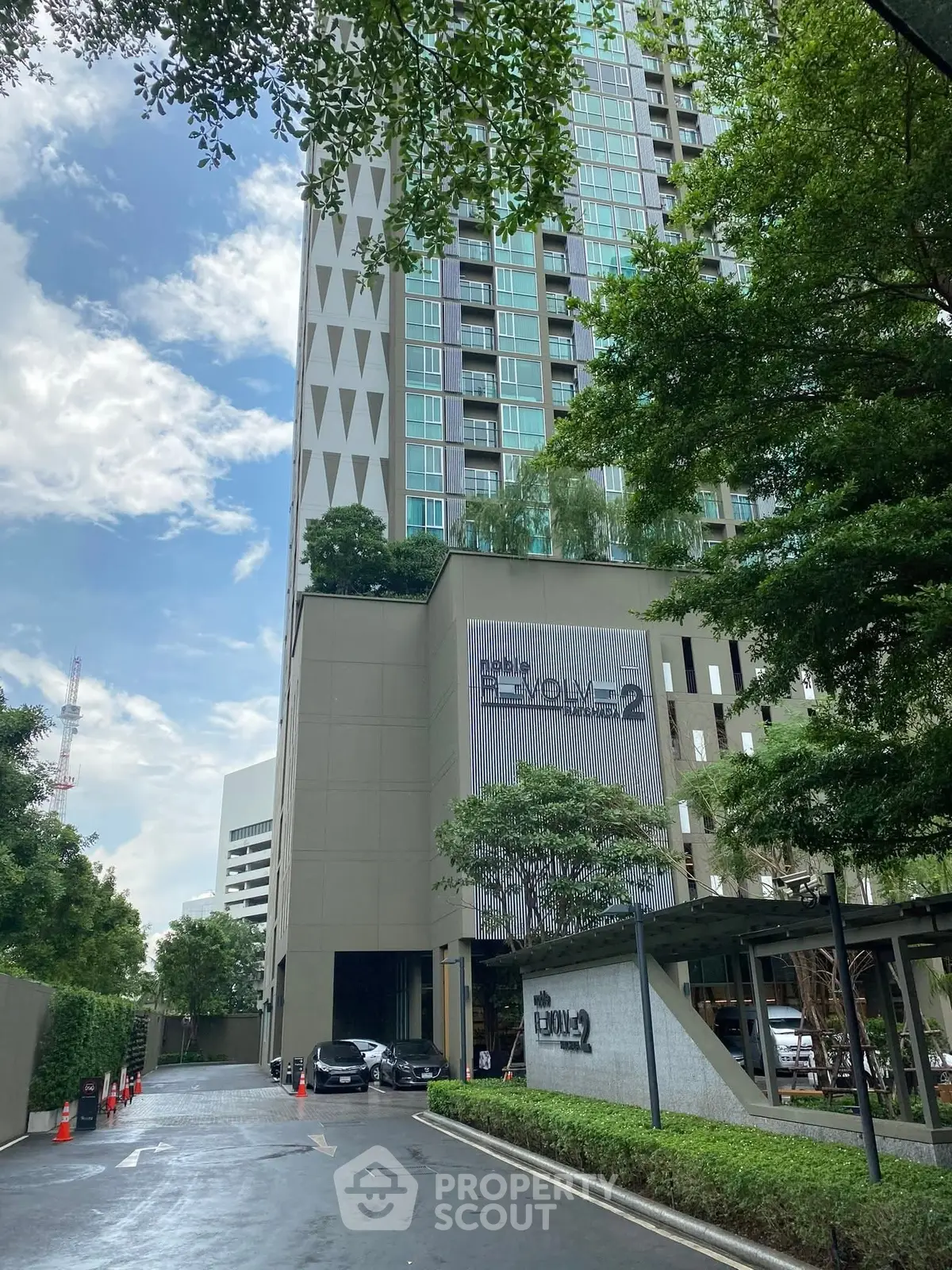 Modern high-rise building with lush greenery and clear blue sky, ideal urban living.