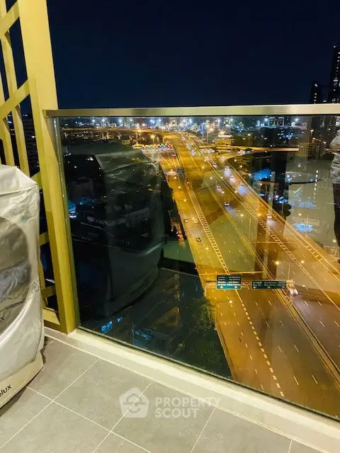 Stunning night view from a high-rise balcony overlooking a bustling city highway.