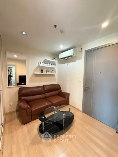 Cozy living room with brown leather sofa and modern glass coffee table, perfect for relaxation.