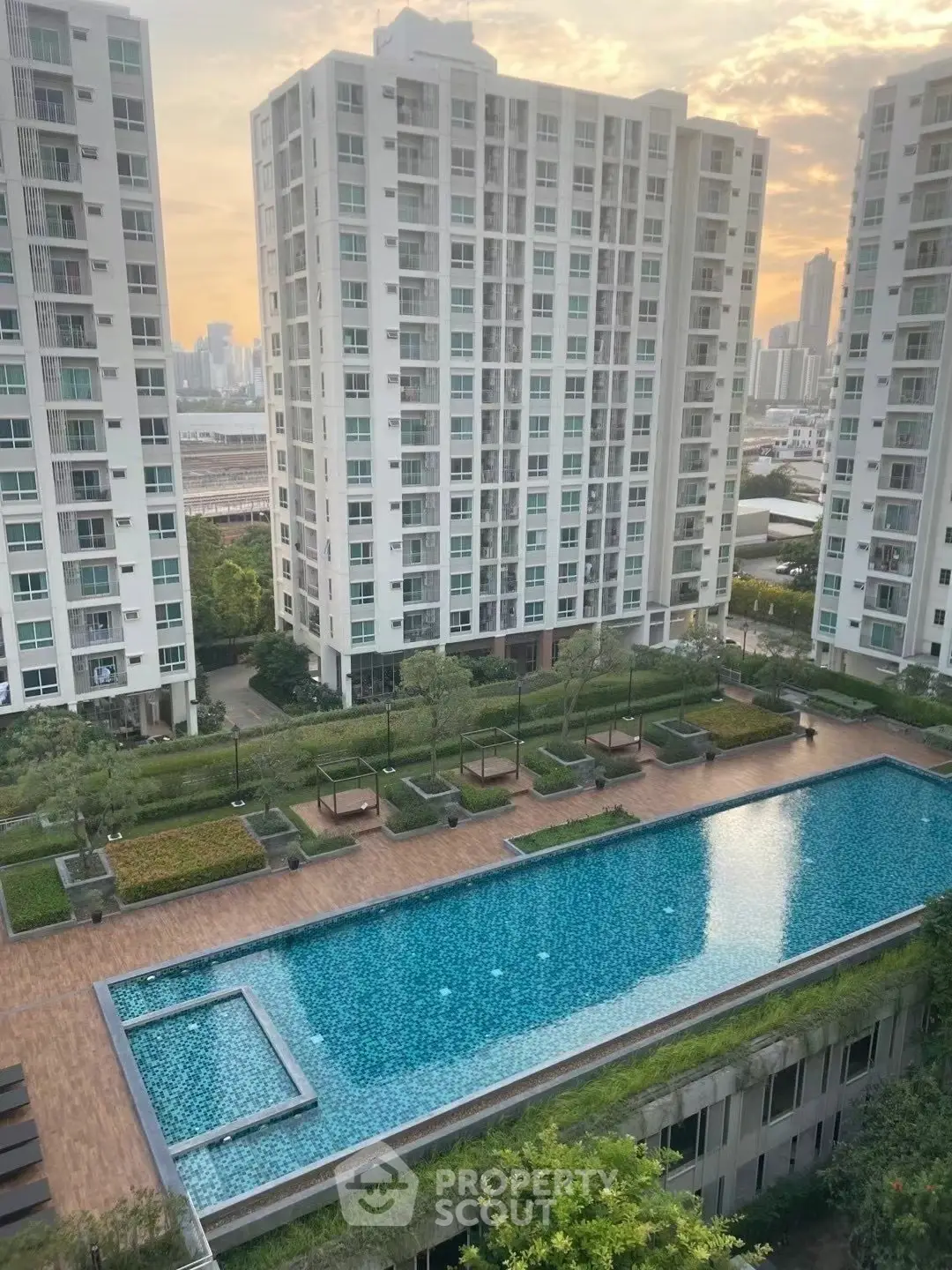 Luxurious high-rise apartment complex with stunning pool and city views at sunset.