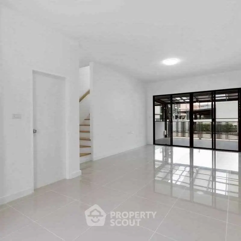 Spacious modern living room with large windows and glossy tiled floors.