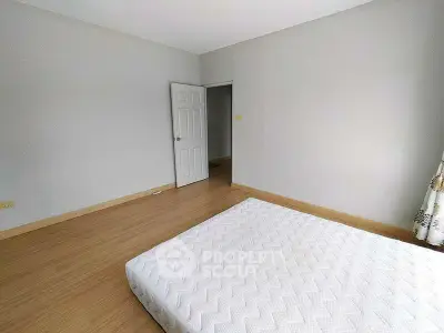 Spacious bedroom with minimalist decor and wooden flooring