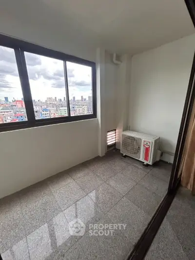 High-rise apartment balcony with city skyline view and air conditioning unit.
