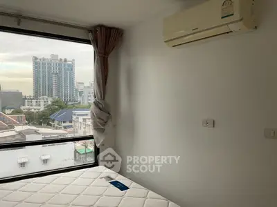 Modern bedroom with large window and city view, featuring air conditioning and minimalist decor.
