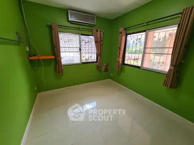 Vibrant green-walled room with gleaming tiled floors, ample natural light, and air conditioning unit, perfect for a cozy living space.