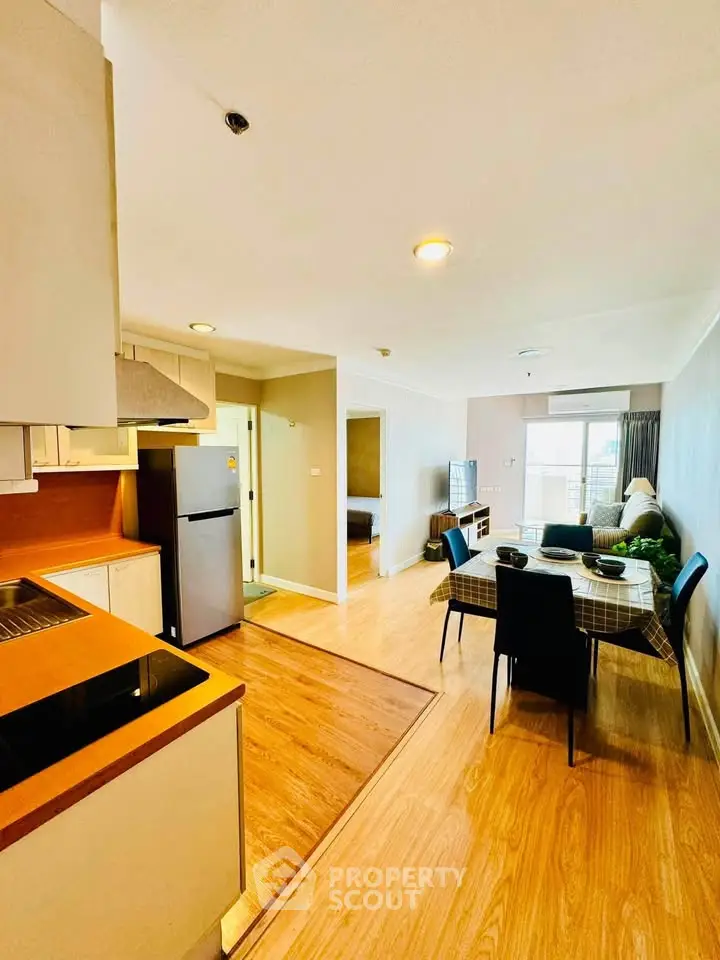 Spacious open-plan living room with modern kitchen and dining area, featuring stylish decor and ample natural light.