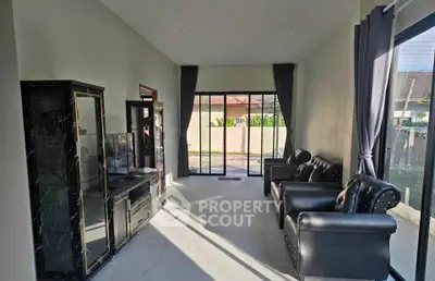 Spacious living room with modern black leather furniture and large windows offering natural light.