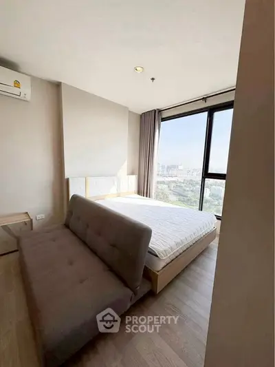 Modern bedroom with city view, featuring a cozy bed and stylish sofa.