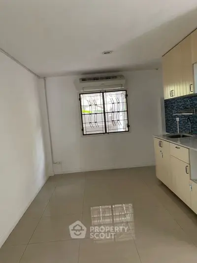Spacious kitchen area with modern cabinetry and tiled flooring in a bright apartment.