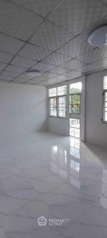 Spacious empty room with large windows and glossy tiled floor, perfect for customization.