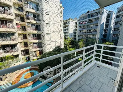 Spacious balcony with safety net overlooking apartment complex and pool