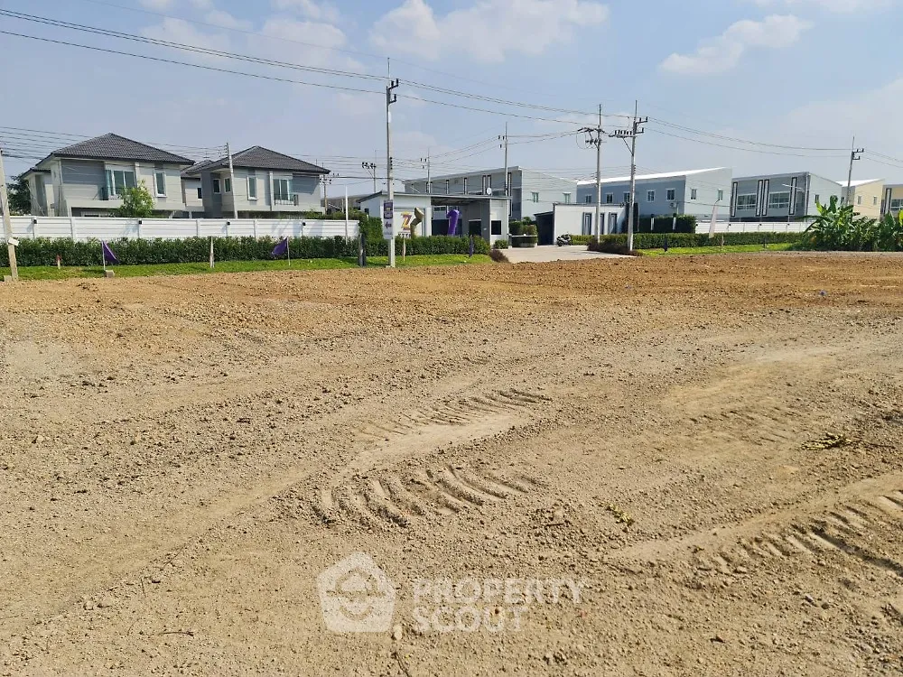Prime residential land for sale with modern houses in the background, ideal for new development.