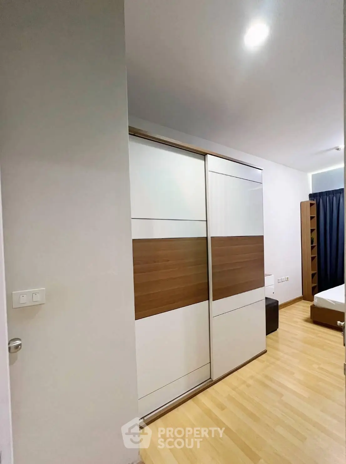 Modern bedroom with sleek sliding wardrobe and wooden flooring