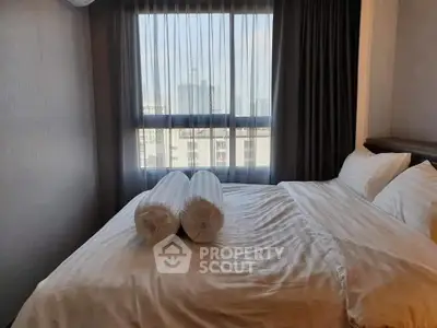 Cozy bedroom with city view, featuring a comfortable bed and elegant curtains.