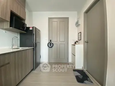 Modern kitchen with sleek cabinetry and stainless steel appliances in a cozy apartment.