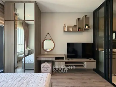 Modern bedroom with stylish decor, large mirror, and sleek TV setup in a cozy apartment.