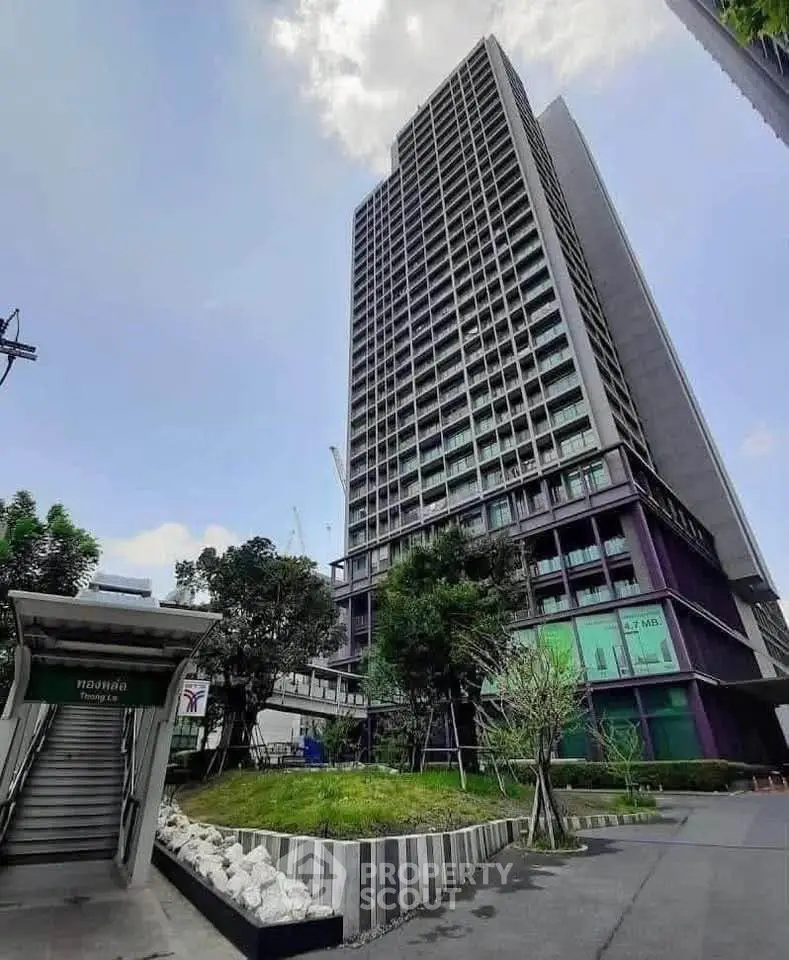 Modern high-rise building with lush greenery and clear blue sky, ideal for urban living.
