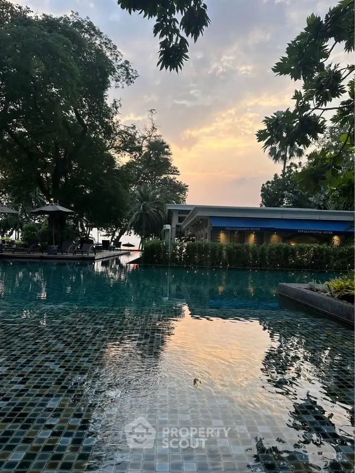 Stunning poolside view at sunset with lush greenery and serene ambiance.