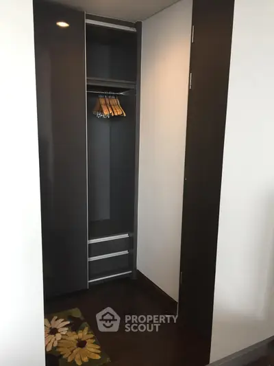 Modern walk-in closet with sleek dark wood finish and ample storage space.