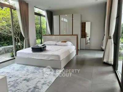 Spacious bedroom with large windows offering abundant natural light, modern furnishings, and direct garden access for a serene living experience.