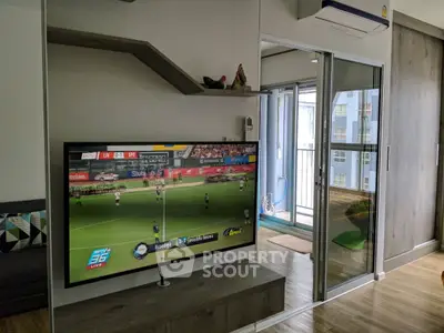 Modern living room with TV and sliding glass doors leading to a balcony in a stylish apartment.
