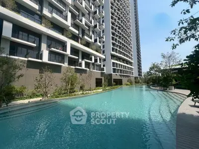 Luxurious modern apartment building with stunning pool and lush greenery.