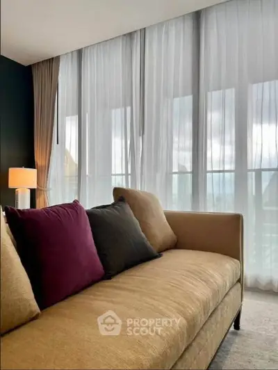 Stylish living room with elegant sofa and floor-to-ceiling windows offering natural light.