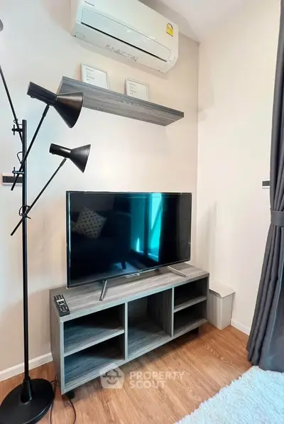 Modern living room corner with TV, stylish lamp, and air conditioning unit.