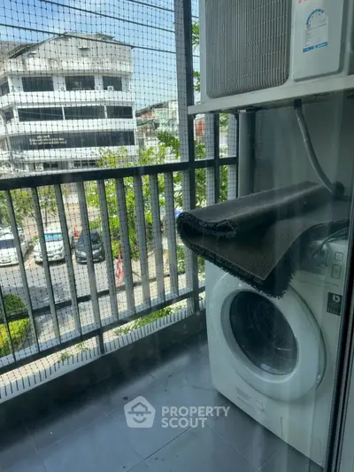 Modern balcony with washing machine and air conditioning unit, offering urban views.