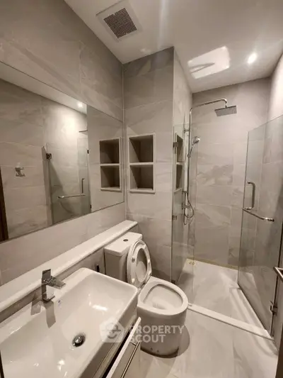 Modern bathroom with glass shower and sleek fixtures in luxury apartment.