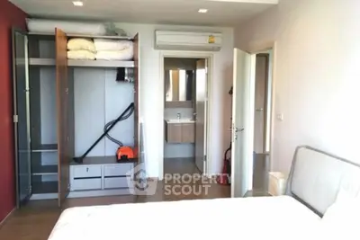 Spacious bedroom with open closet and ensuite bathroom in modern apartment.