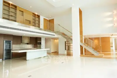 Luxurious open-plan living space with modern kitchen and elegant staircase